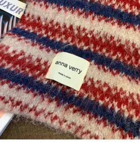 Close-up detail of cozy wool-blend striped knitted winter scarf with brand woven label.