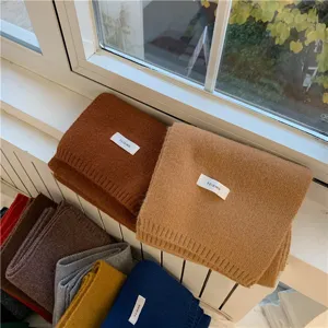 Close-up detail of soft knitted winter scarves neatly stacked in various colors by the window.