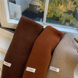 Close-up detail of cozy winter knitted scarves in multiple solid colors, soft texture.