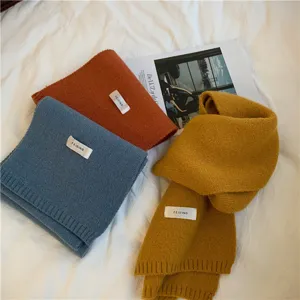 Detailed view of cozy winter knit scarves in solid colors, featuring soft textured fabric and tags.