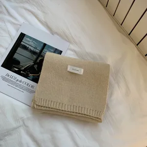 Dettaglio di sciarpa in maglia beige con tessuto di lana morbida ed etichetta stile.