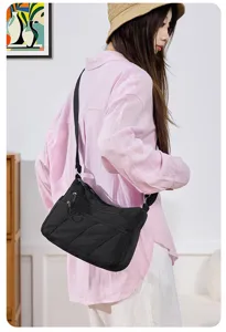 Detail view of black nylon crossbody bag, showing multi-zipper pockets and adjustable strap.