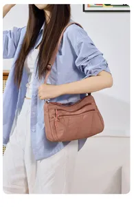 Detail view of washed nylon crossbody bag with zipper pockets worn in daily casual scene.