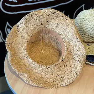 Gros plan d'un chapeau de soleil en paille ajourée avec texture tissée et doublure intérieure.