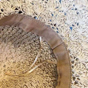 Détail intérieur d'un chapeau de paille artisanal, design ajouré respirant pour vacances à la plage.