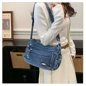 Detailed shot of a stylish retro denim crossbody bag featuring multiple zipper pockets and metal accents.