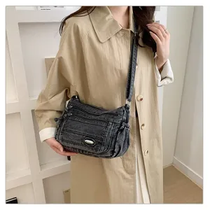 Details of the casual washed denim crossbody bag featuring multiple zipper pockets and strap.