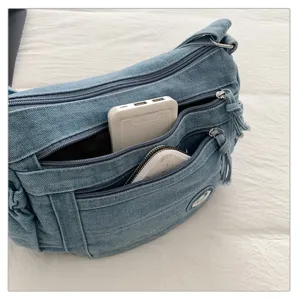 Detailed view of blue denim crossbody bag with multiple zipped pockets and large capacity storage.