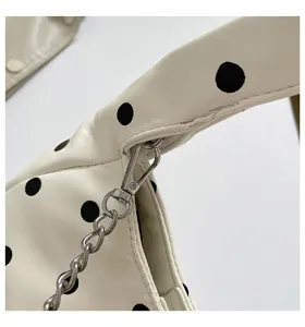 Close-up detail view of white polka dot women handbag featuring silver chain strap hardware.