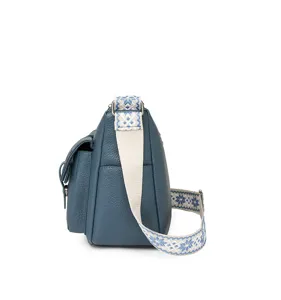Side view of blue soft litchi leather crossbody bag with ethnic wide strap for women.