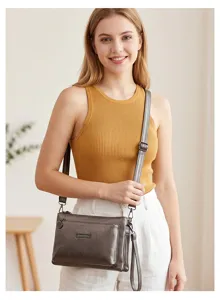 Detailed shot of a stylish dark grey PU leather multi-compartment crossbody bag worn.