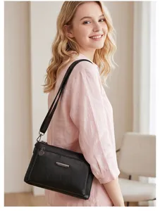 Detail view of black PU leather shoulder bag with metal logo plate and zipper design.