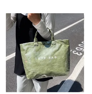 Dettaglio borsa shopper impermeabile in PVC verde con trama chiara e scritta.