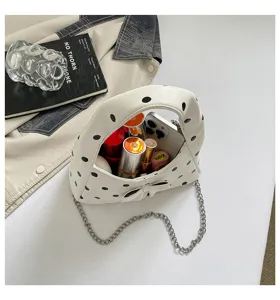 Detailed view of a stylish polka dot underarm dumpling bag with bow and metal chain strap.