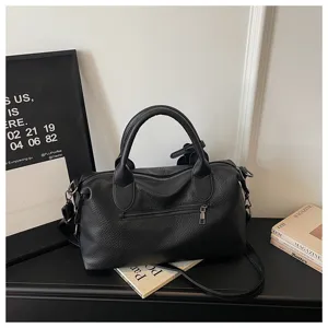 Close-up detail of black soft leather retro shoulder bag with zipper pocket and metal hardware.
