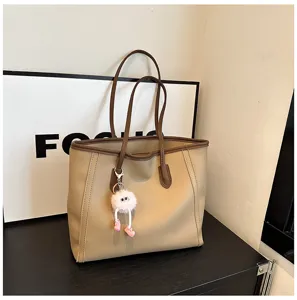 Retro large capacity tote bag for women, stylish contrast color shoulder bag with cute plush pendant.