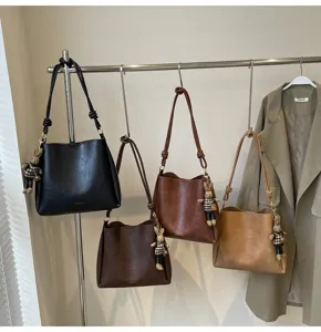 Detailed view of women's vintage shoulder tote bags hanging on a rack in multiple colors.