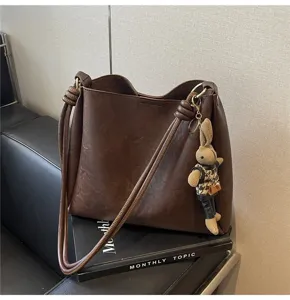 Detailed view of a vintage dark brown shoulder tote bag with a cute plush bunny charm.