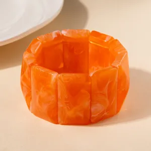 Gros plan d'un bracelet en acrylique orange vif avec des motifs marbrés blancs