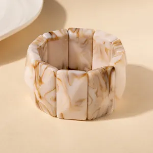 Détail rapproché d'un bracelet en acrylique avec des motifs marbrés marron et crème