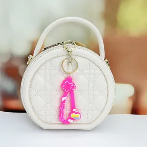 White round handbag featuring stylish quilted pattern and cute pink star keychain accessory.