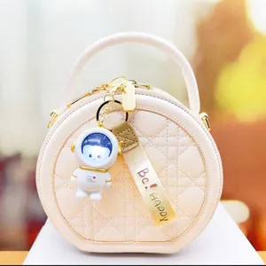 Round quilted handbag with cute astronaut luminous night light keychain and stylish strap.