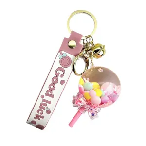 Leuke vloeibare drijfzand lolly sleutelhanger met roze bandje en gouden metalen ringen.