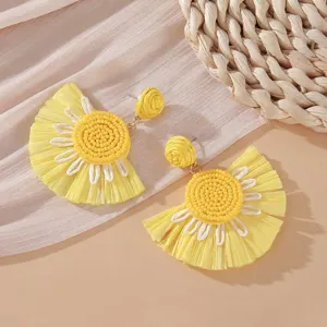 Dettaglio orecchini a fiore in rafia gialla con centro in perline e petali intrecciati