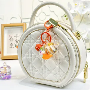 White round quilted handbag with cute orange keychain pendant stylish chic accessory