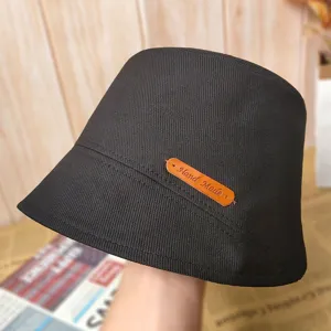Détail de chapeau bob noir en coton de qualité supérieure avec étiquette en cuir fait main.