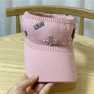 Dettaglio di un bellissimo cappello da sole rosa in maglia con strass scintillanti e perle.