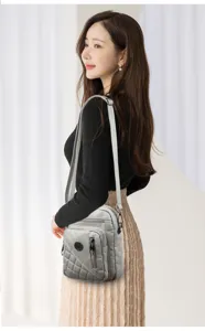 Grey washed leather cross-body shoulder bag with multi-layer zippers and chic quilted design.