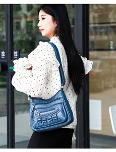 Detail shot of multi-pocket soft leather shoulder bag with chic braided strap and zipper.