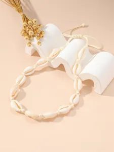 Primo piano di una collana di conchiglie di ciprea su un supporto ondulato bianco