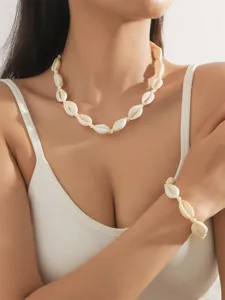 Primo piano di una modella che indossa una collana e un braccialetto di conchiglie naturali