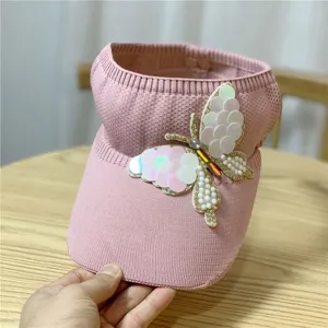 Primo piano dettagliato del cappello parasole rosa in maglia con farfalla di strass.