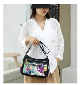 Nylon multi-zipper shoulder crossbody bag for women with colorful abstract print front pocket.