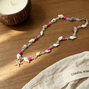 Close-up of handmade shell necklace with pink beads and a gold starfish charm.