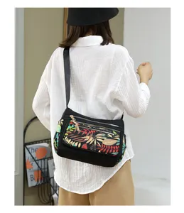 Detailed back view of the black nylon crossbody bag featuring colorful leaf print flap.