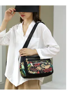 Detail view of nylon crossbody bag with colorful leaf print, multi-zipper and adjustable strap.