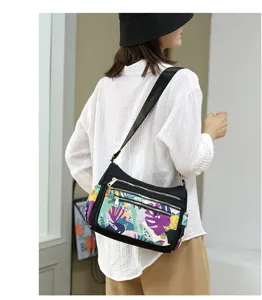 Colorful printed nylon crossbody bag detail showing multi-layer zippers and adjustable strap.