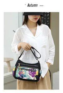 Multi-pocket nylon crossbody shoulder bag with colorful abstract front pocket pattern detail.