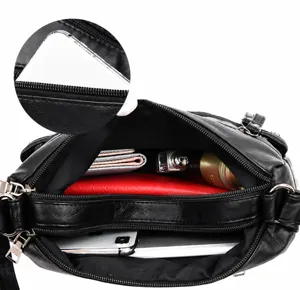 Black soft leather shoulder bag interior capacity detail view, multiple zipper pockets.
