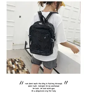 Detail shot of black glossy PVC backpack worn by model, featuring large capacity for students.