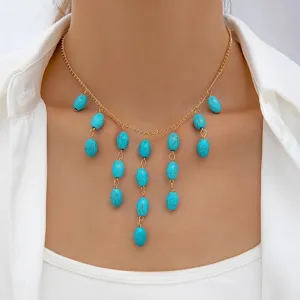Close-up detail of vintage turquoise oval bead necklace with golden chain worn by female model