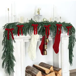 Christmas fireplace decoration set with green pine garland and red velvet bows and stockings.