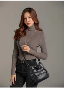 Detail view of women's black soft leather crossbody bag with multi-zipper pockets worn by model.