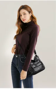Detail shot of women's soft leather multi-zipper shoulder and crossbody bag styling.