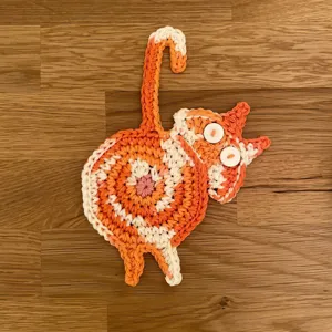 Gros plan détaillé de sous-verre chat tricoté orange et blanc pour décoration de table.