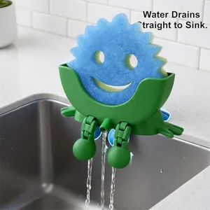 Detailed view of the green frog sponge holder draining directly into the kitchen sink.